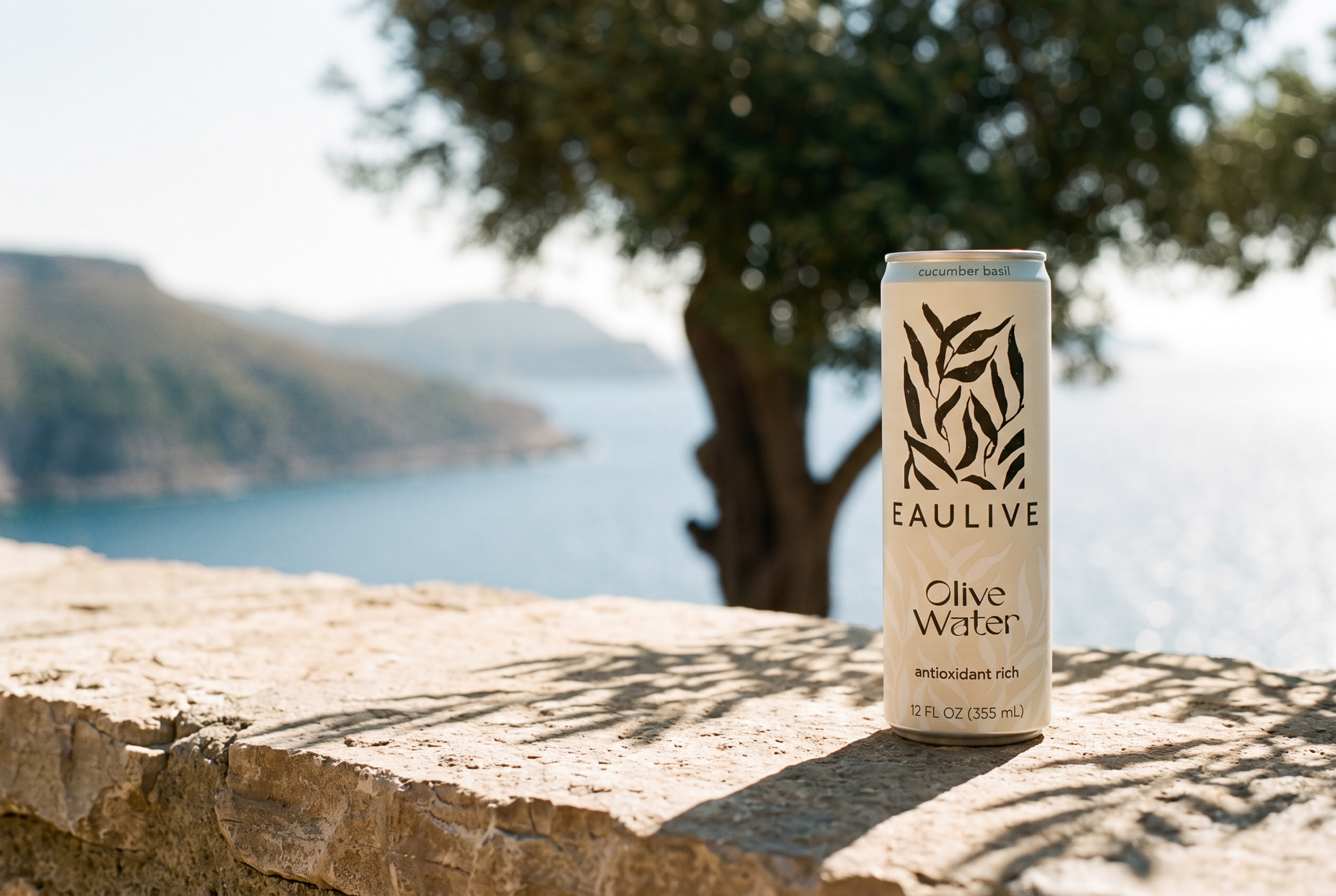 A slim EAULIVE olive water can on a sun-bleached stone ledge above the Mediterranean sea
